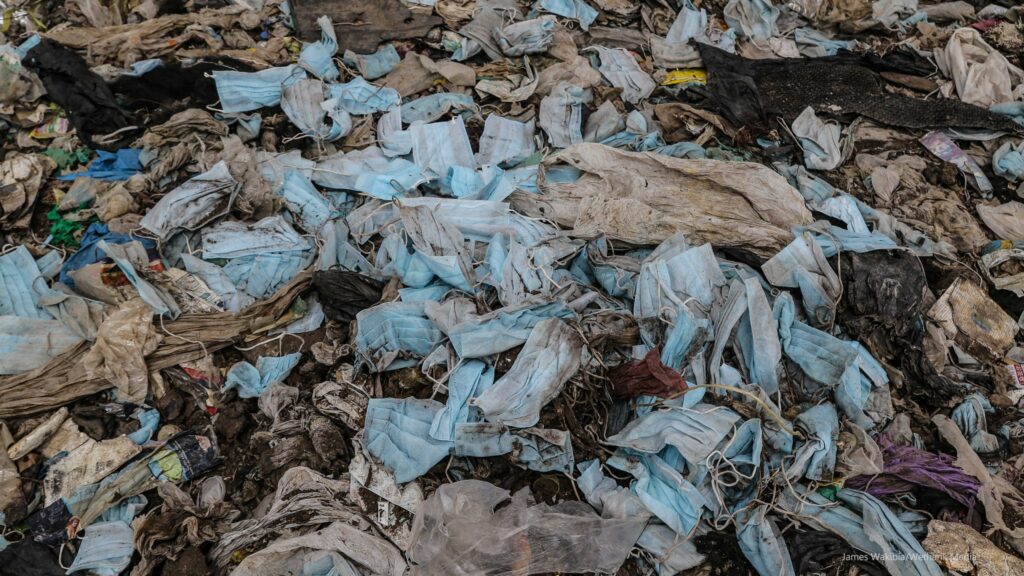 photograph of a dirty pile of discarded facemasks and plastic gloves