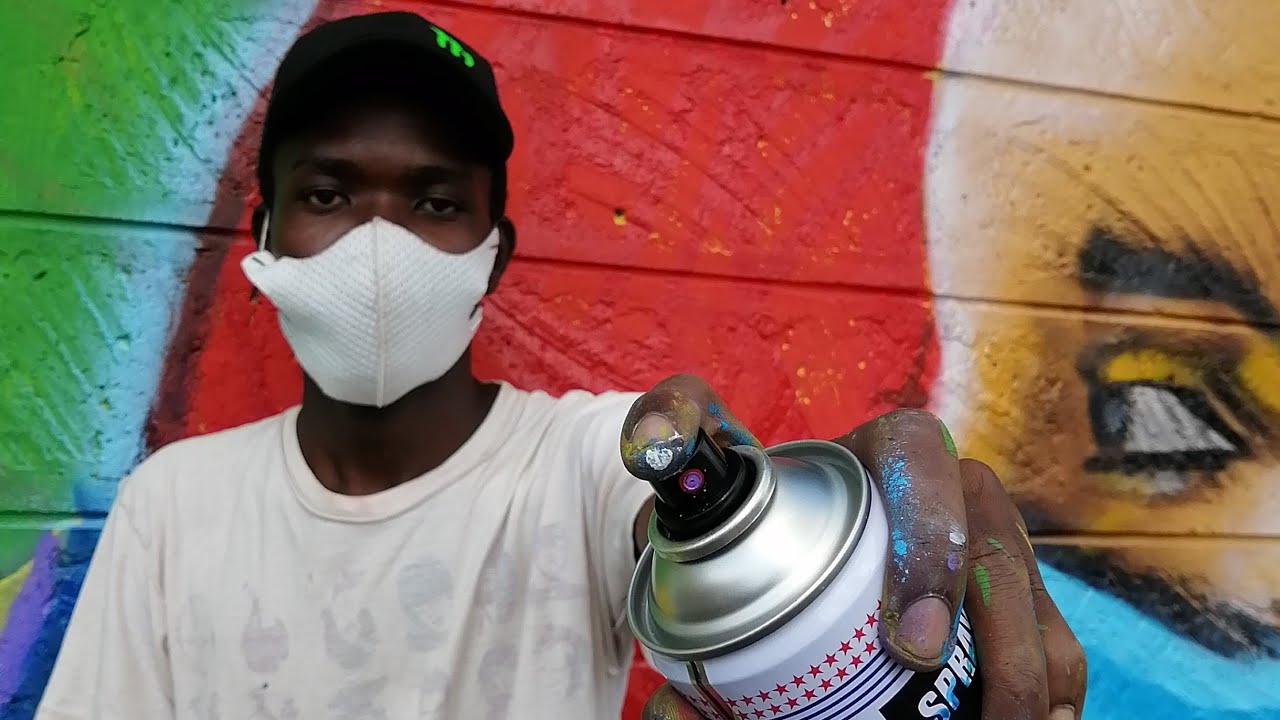 photo of a man holding a spray-paint can, wearing a facemask
