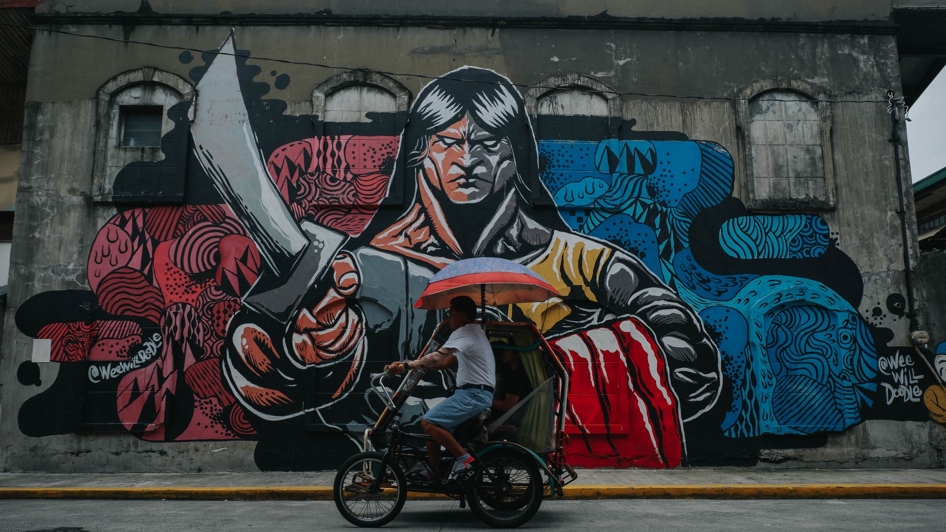 photo of a rickshaw, graffiti mural in the background 