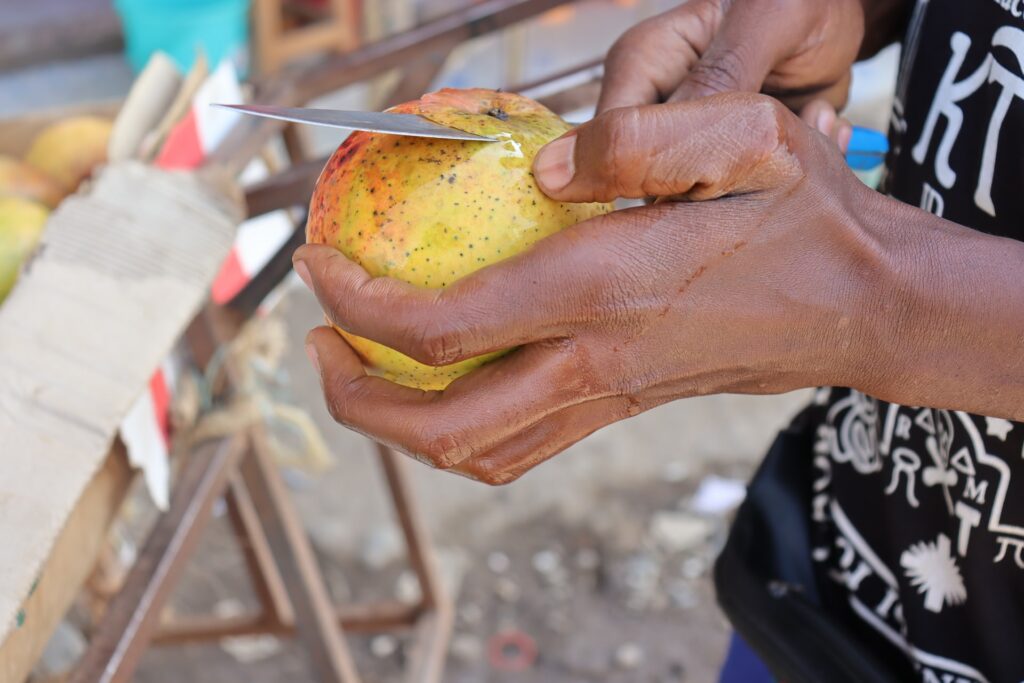 photo of a person peeling a mango
